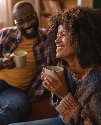 couple each holding a coffee cup, laughing and smiling