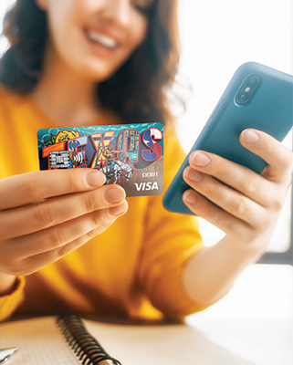 Girl wearing bright yellow top, holding her cellphone and her Texas Bank and Trust Visa debit card that has Texas in big letters across the card